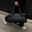 Stubble & Co gym duffel bag held by top handle with adjustable strap, black