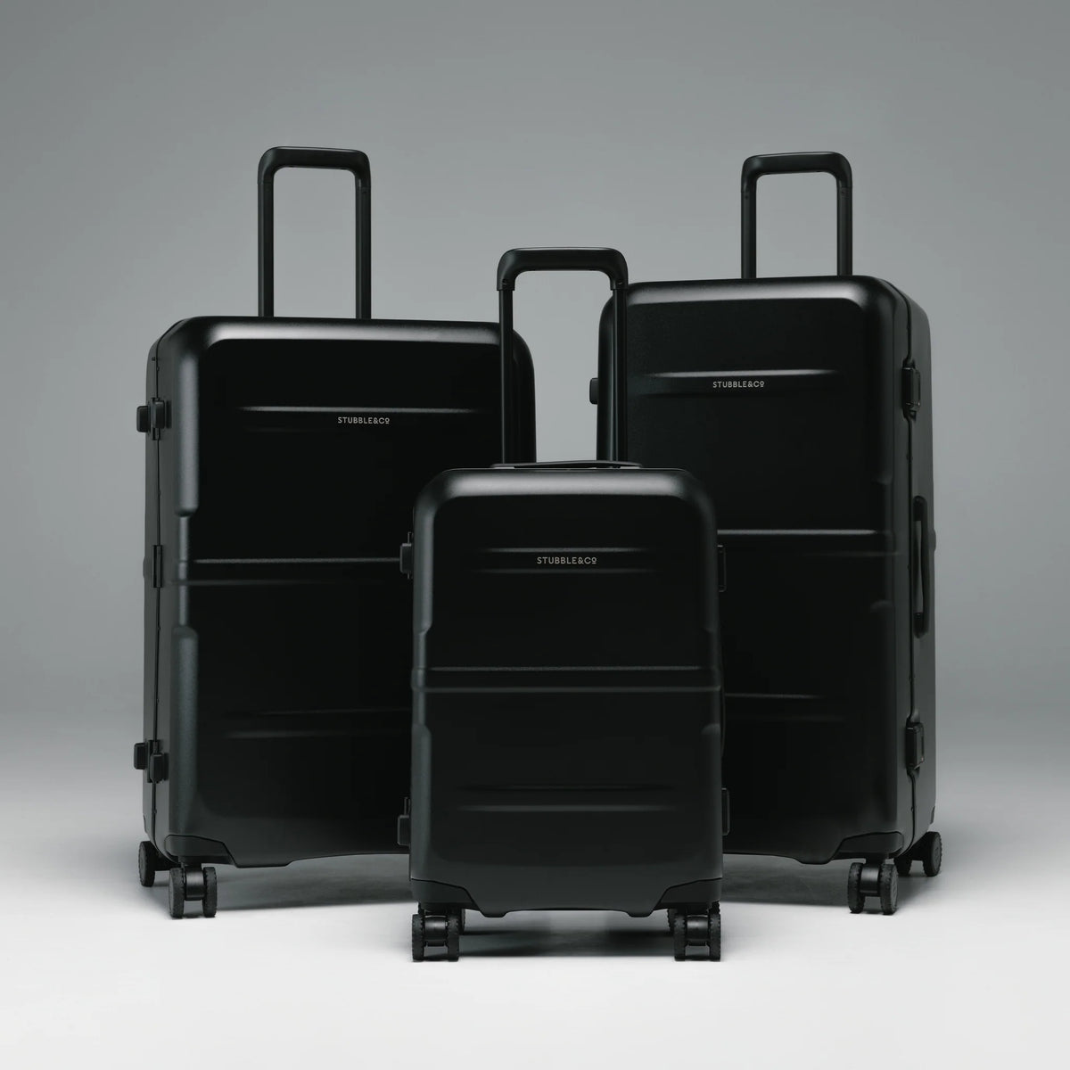 Stacked black hard-shell luggage set with telescopic handles and spinner wheels