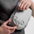 Ash gray sling bag close-up of front pocket zipper and drawcord toggles