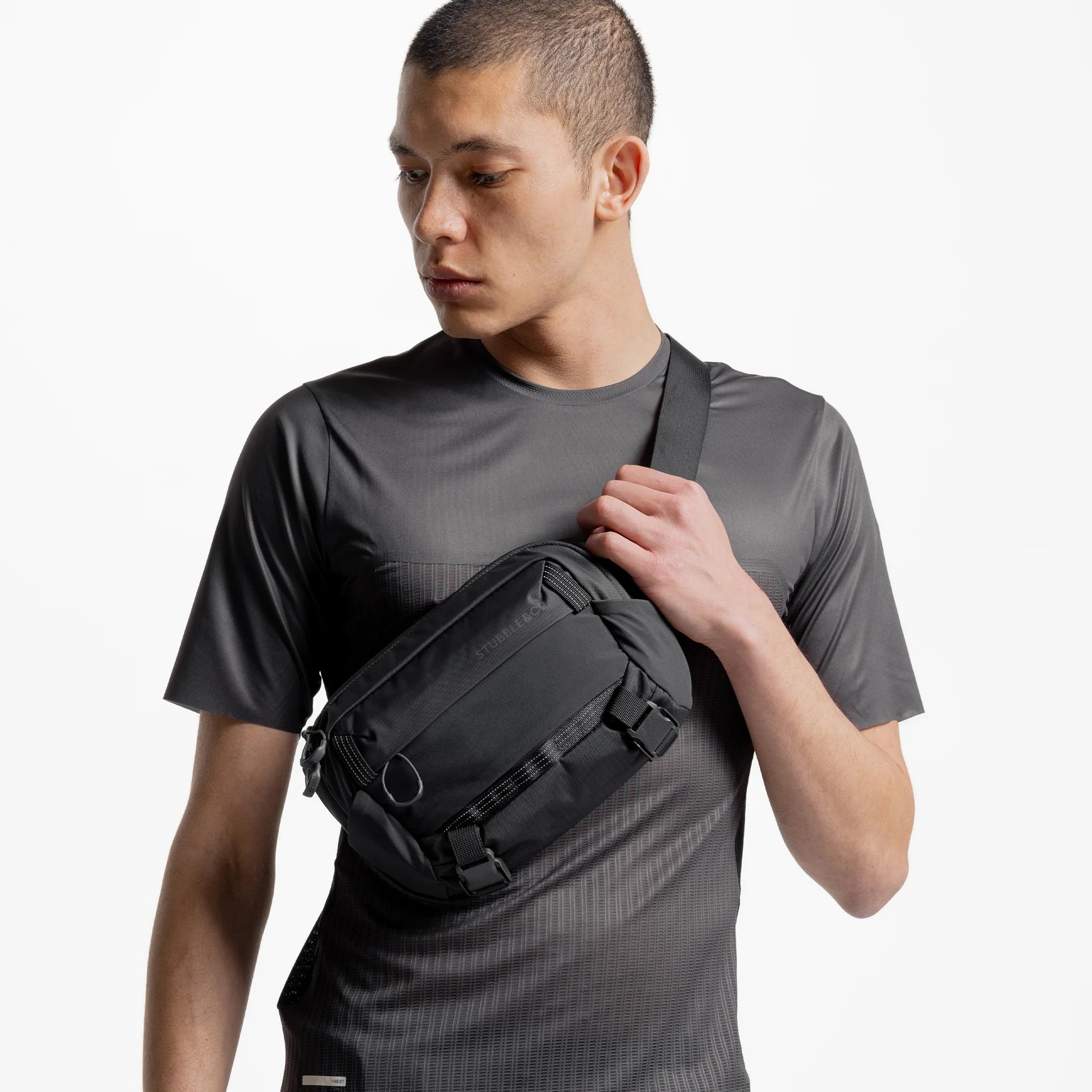 Charcoal crossbody sling bag worn over T-shirt with adjustable shoulder strap