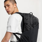 Dark gray backpack worn on shoulders with front zip pocket and side storage panel
