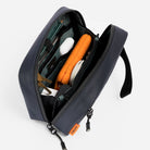 Waterproof tech bag open with interior pockets and gear in dark blue